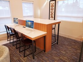 A modern office space with a white desk, black chairs, a computer, and a patterned carpet.