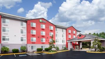 Guests enter through a covered walkway to the main entrance, where a red facade and white accents welcome them.