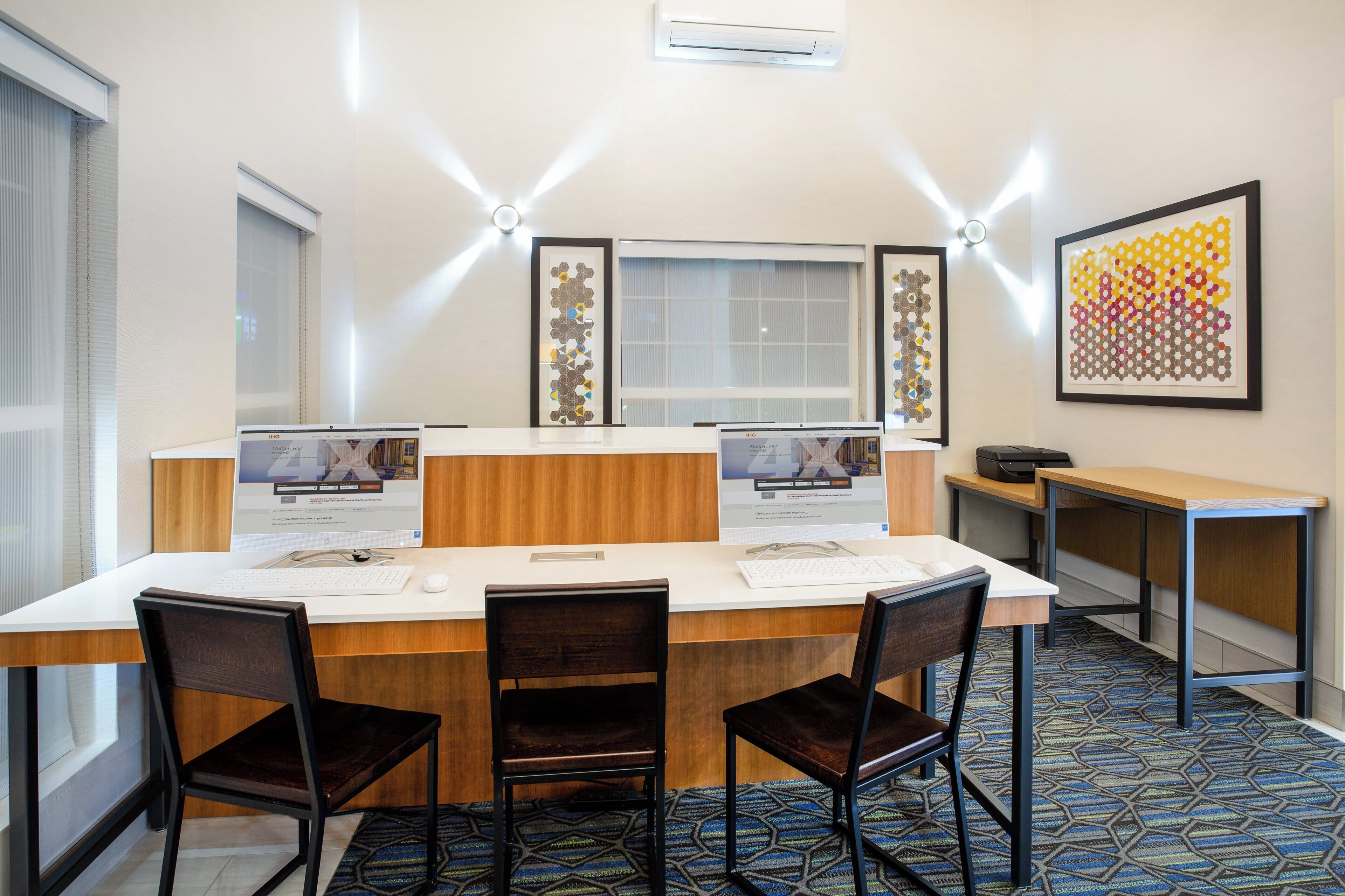 A conference room with a long table, two monitors, and a printer.