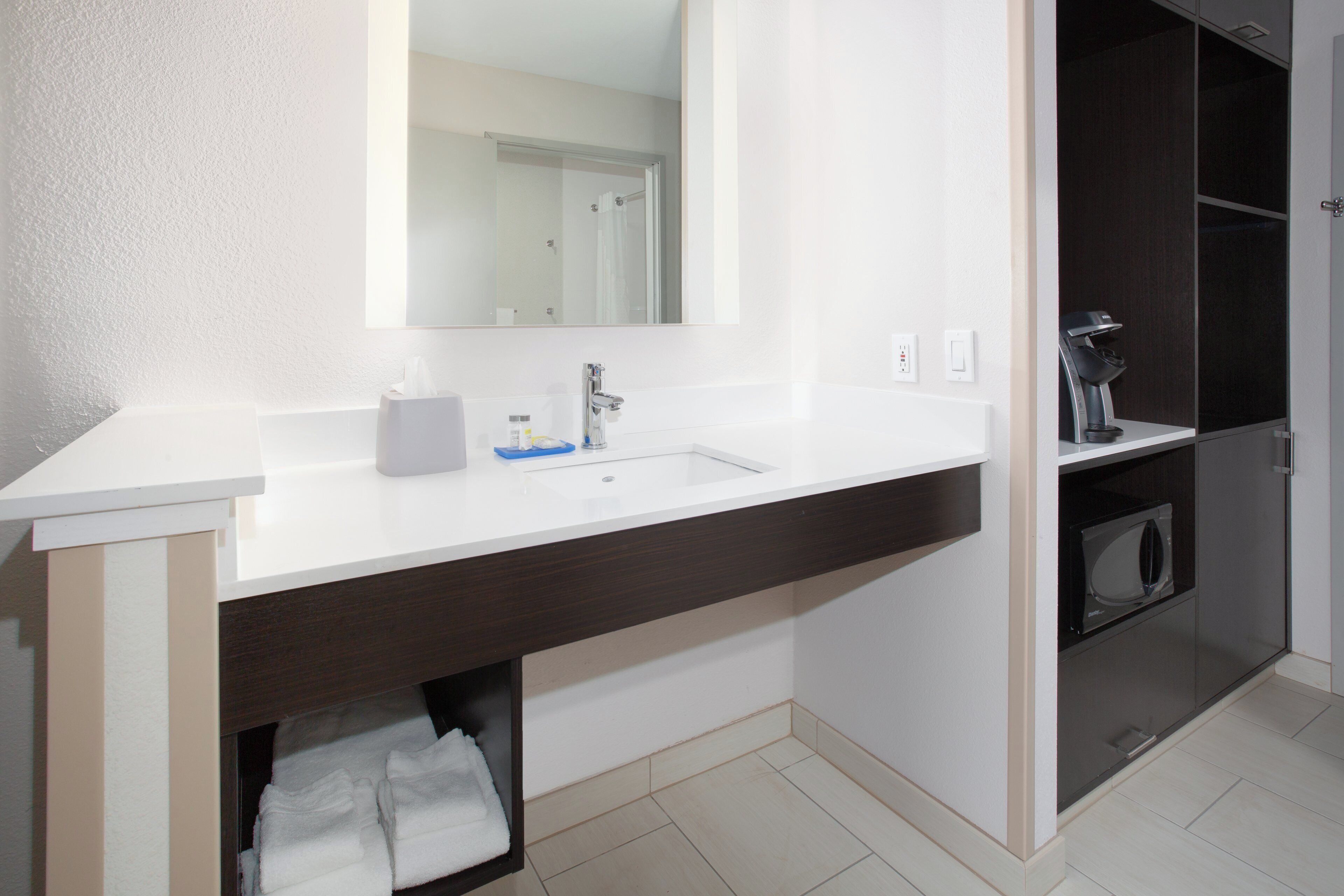 Une salle de bain moderne avec un lavabo blanc, un miroir et un meuble-lavabo en bois foncé.