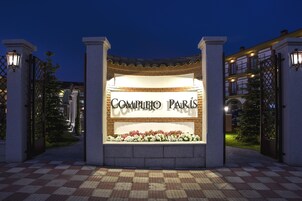 Entrada de un hotel con un letrero que dice "Complejo Paris" y un camino empedrado.