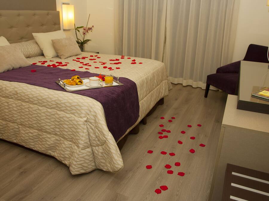 A hotel room with a large bed, a desk, and a chair.
