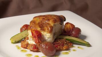 A white plate with a piece of meat, vegetables, and sauce.