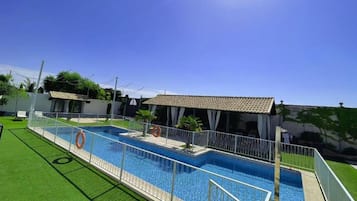 Una piscina con zona vallada, un flotador salvavidas y una zona de estar techada.