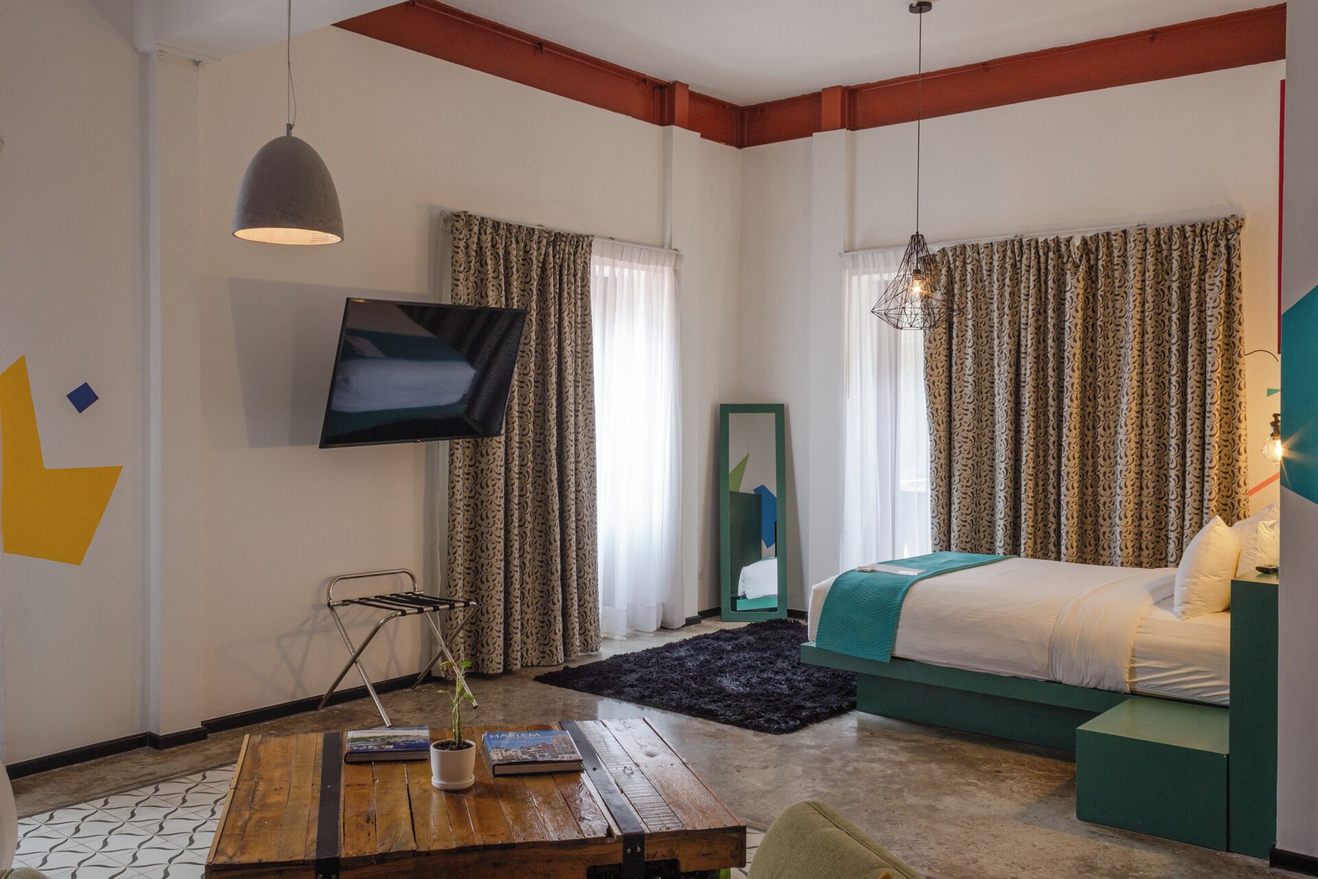 Habitación de hotel moderna con cama, televisor, una mesita de madera y vistas a la ciudad.