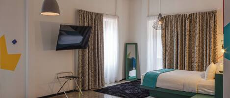 Habitación de hotel moderna con cama, televisor, una mesita de madera y vistas a la ciudad.