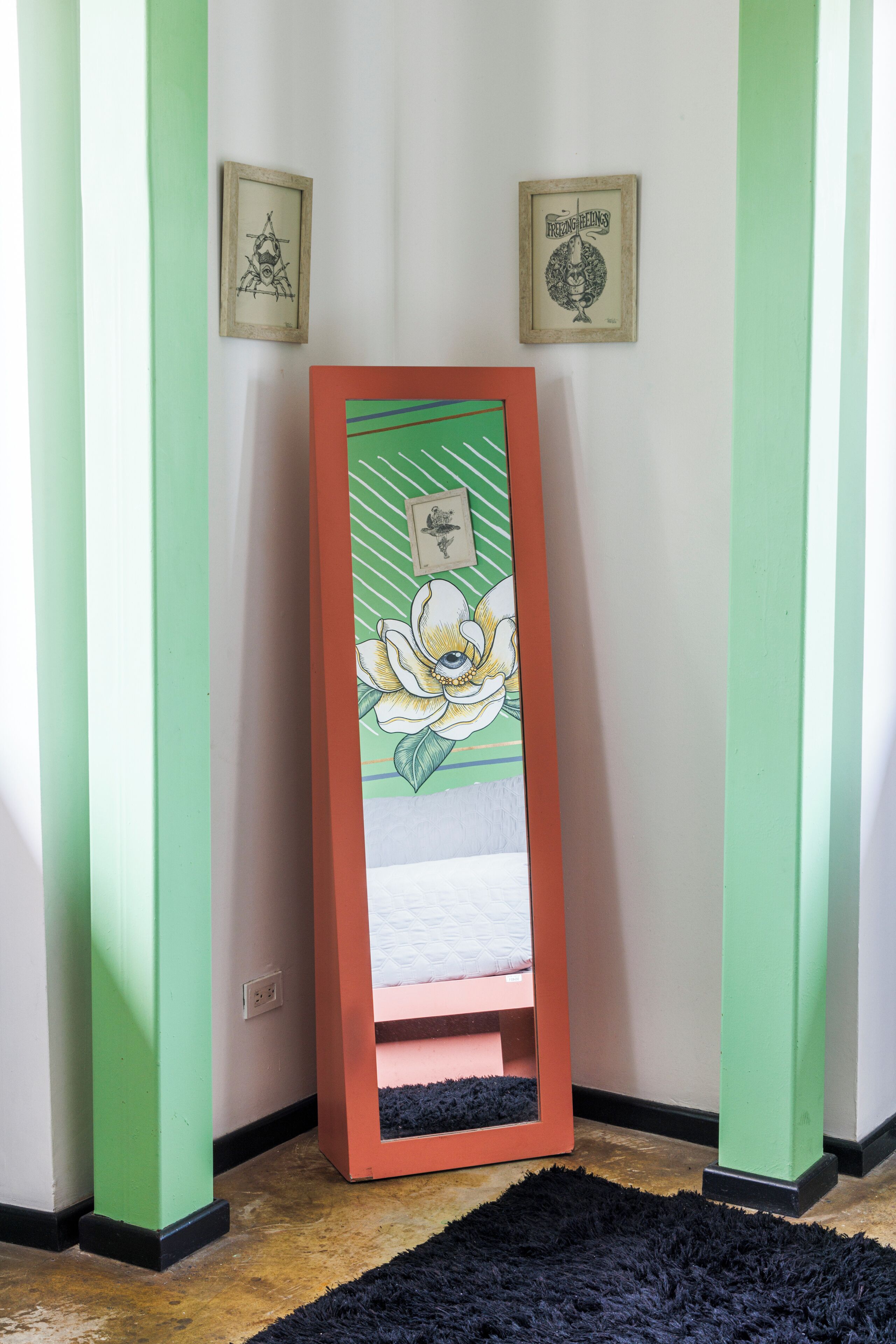 A corner with a framed artwork, a black rug, and green-painted walls.