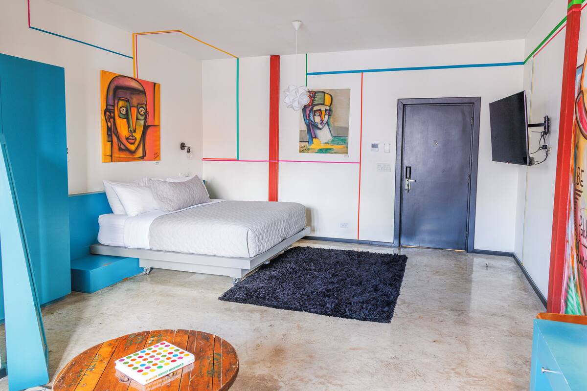 Une chambre à coucher moderne, équipée d’un lit, d’un téléviseur à écran plat et d’œuvres d’art accrochées aux murs.