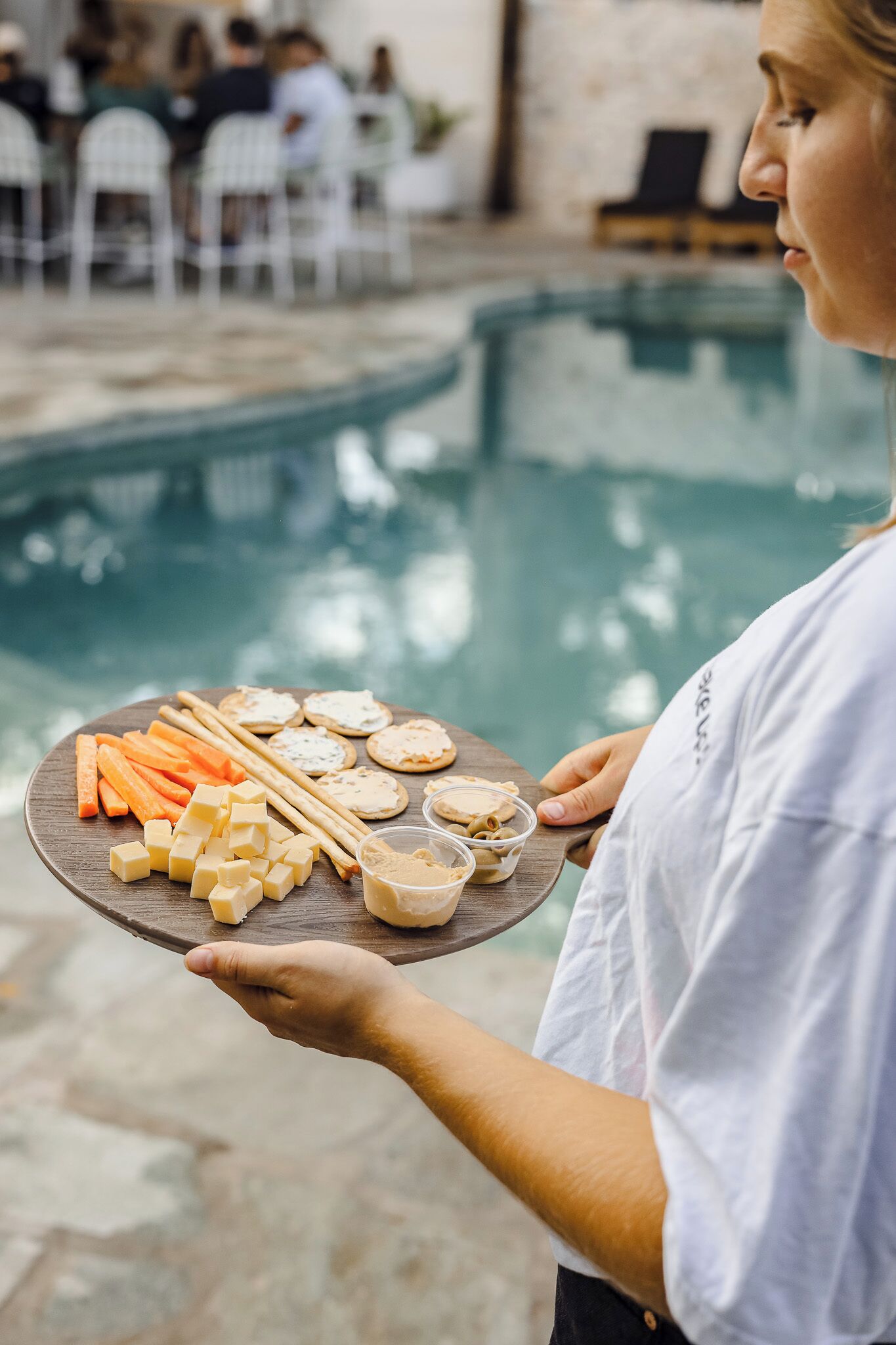 Pessoa segurando uma bandeja com diversos alimentos perto de uma piscina.