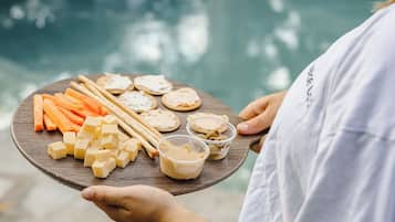 Pessoa segurando uma bandeja com diversos alimentos perto de uma piscina.