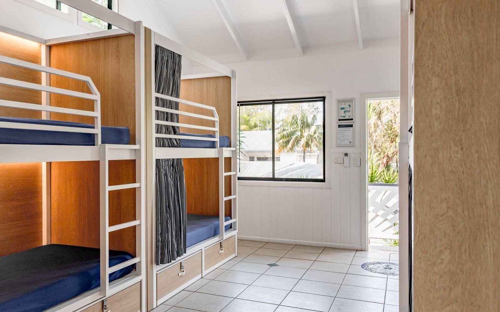 A bunk bed room with a window and a door.