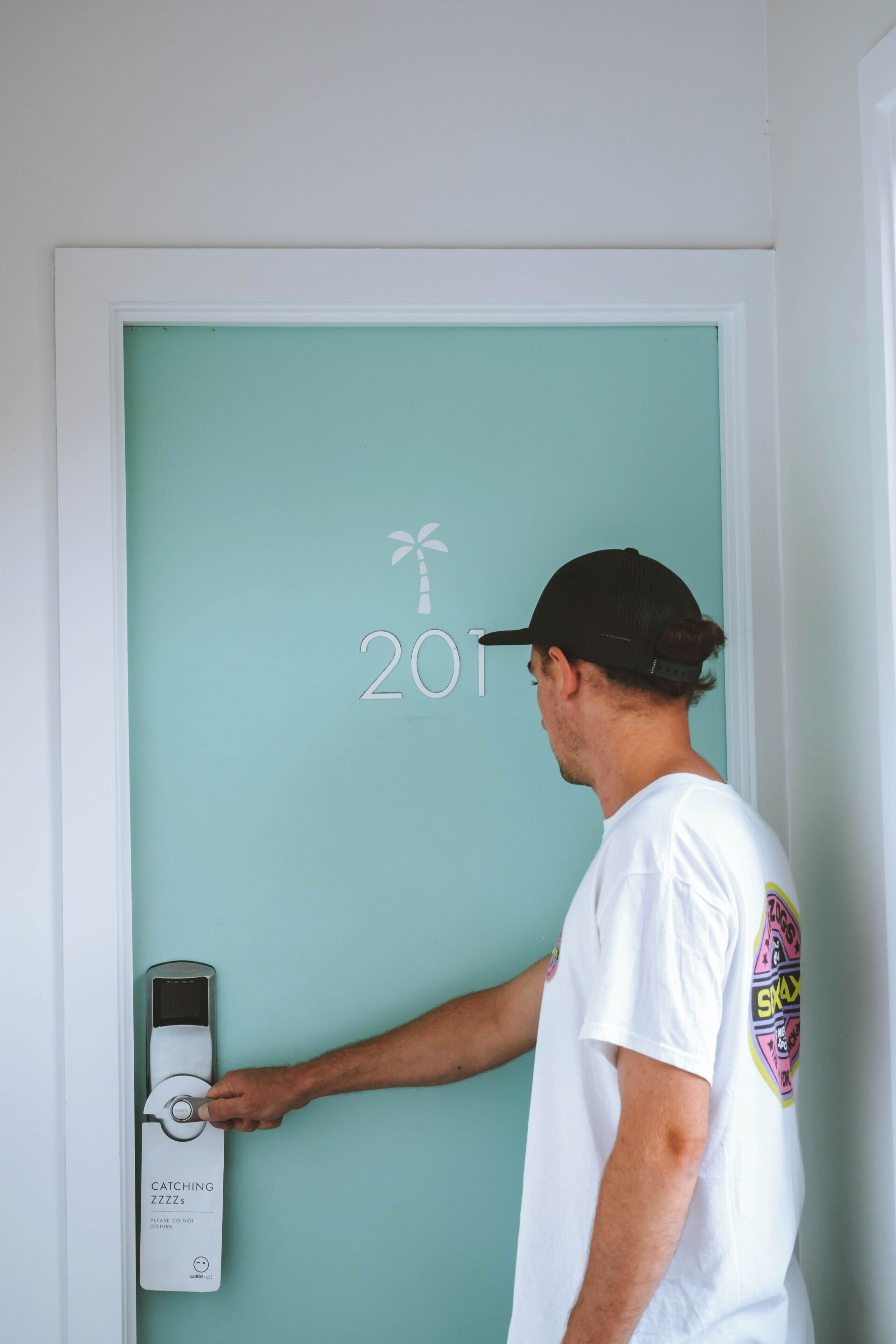 A person using a door intercom with a palm tree and the year 2017 on the door.