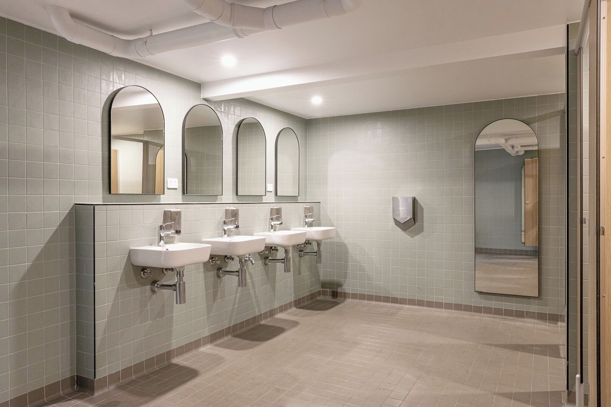 Eine Toilette mit drei Waschbecken, einem Spiegel und einem Urinal.
