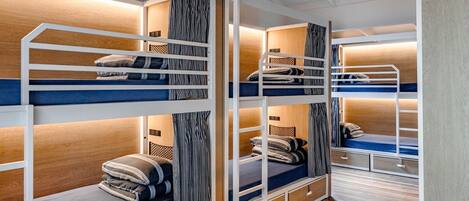 Dormitorio con literas, paredes de madera, techo blanco y suelo de madera.