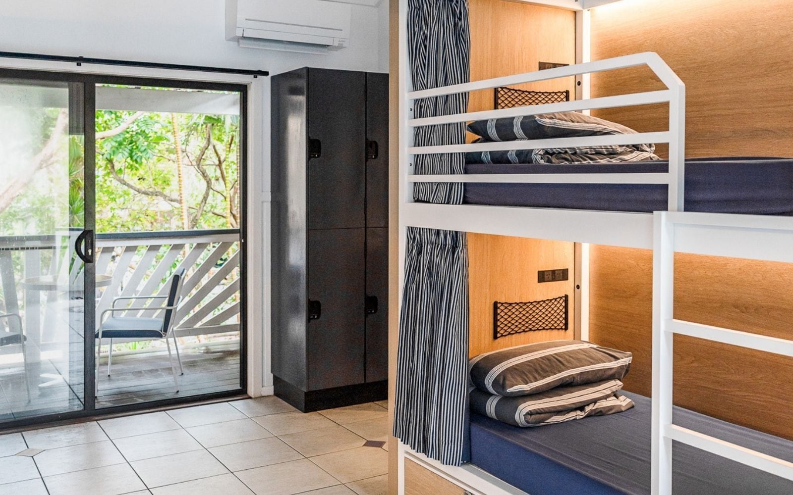 Um quarto com beliche, uma porta de correr de vidro que dá para uma área externa e um guarda-roupa.