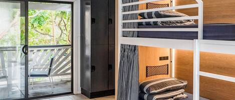 A room with a bunk bed, a sliding glass door leading to an outdoor area, and a wardrobe.