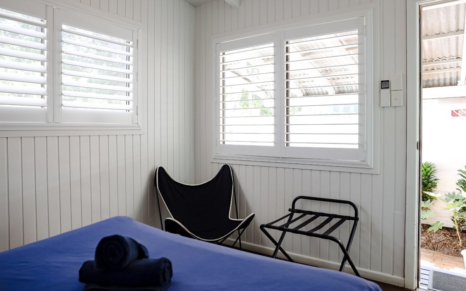 Una habitación con cama, una silla y un tendedero.