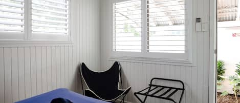 Una habitación con cama, una silla y un tendedero.
