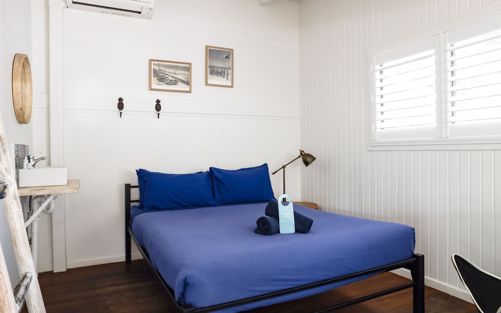 A bedroom with a bed, a nightstand, a lamp, and two framed pictures on the wall.