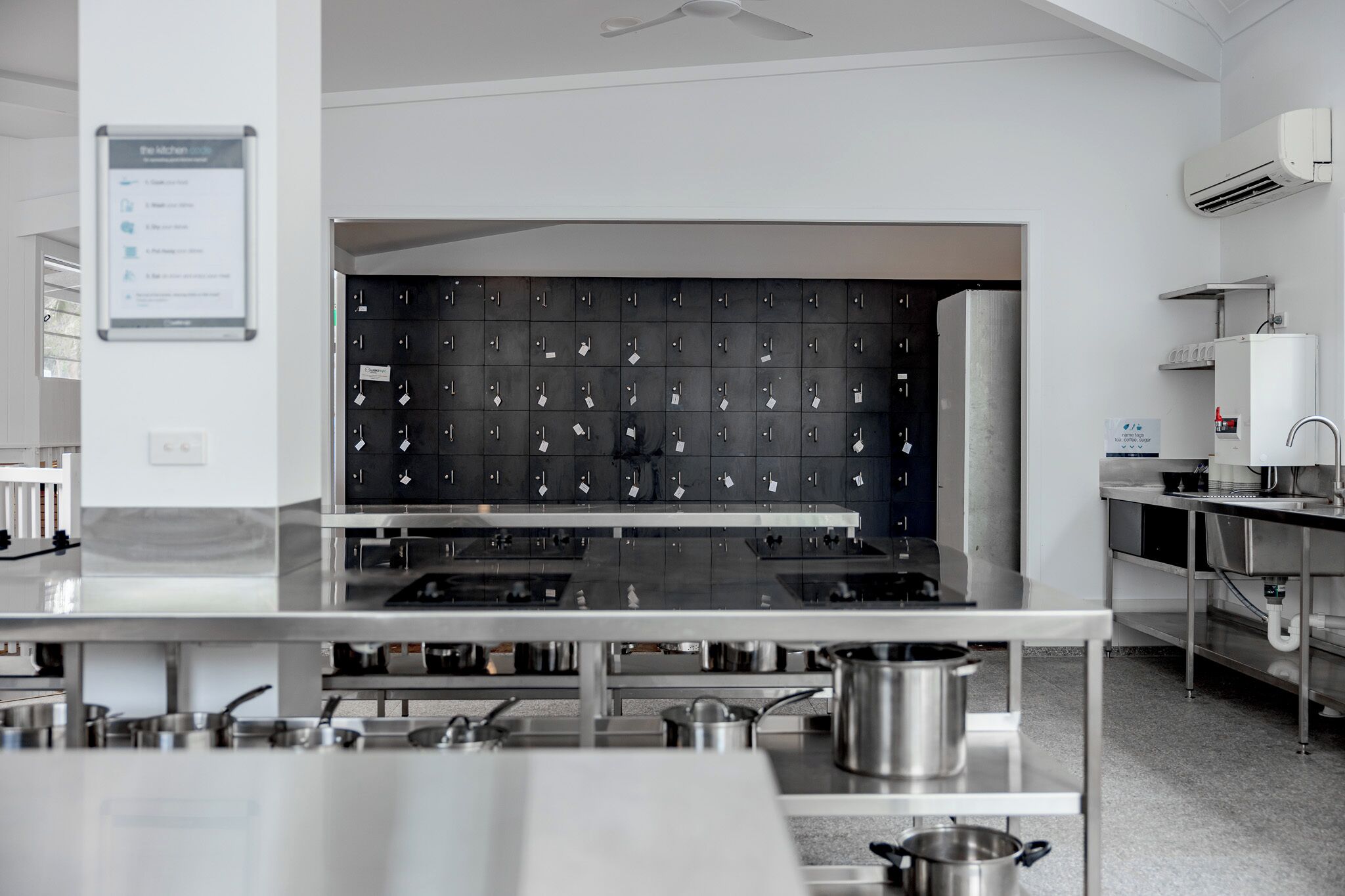 A modern kitchen with stainless steel appliances, a wall-mounted storage unit, and a ceiling fan.