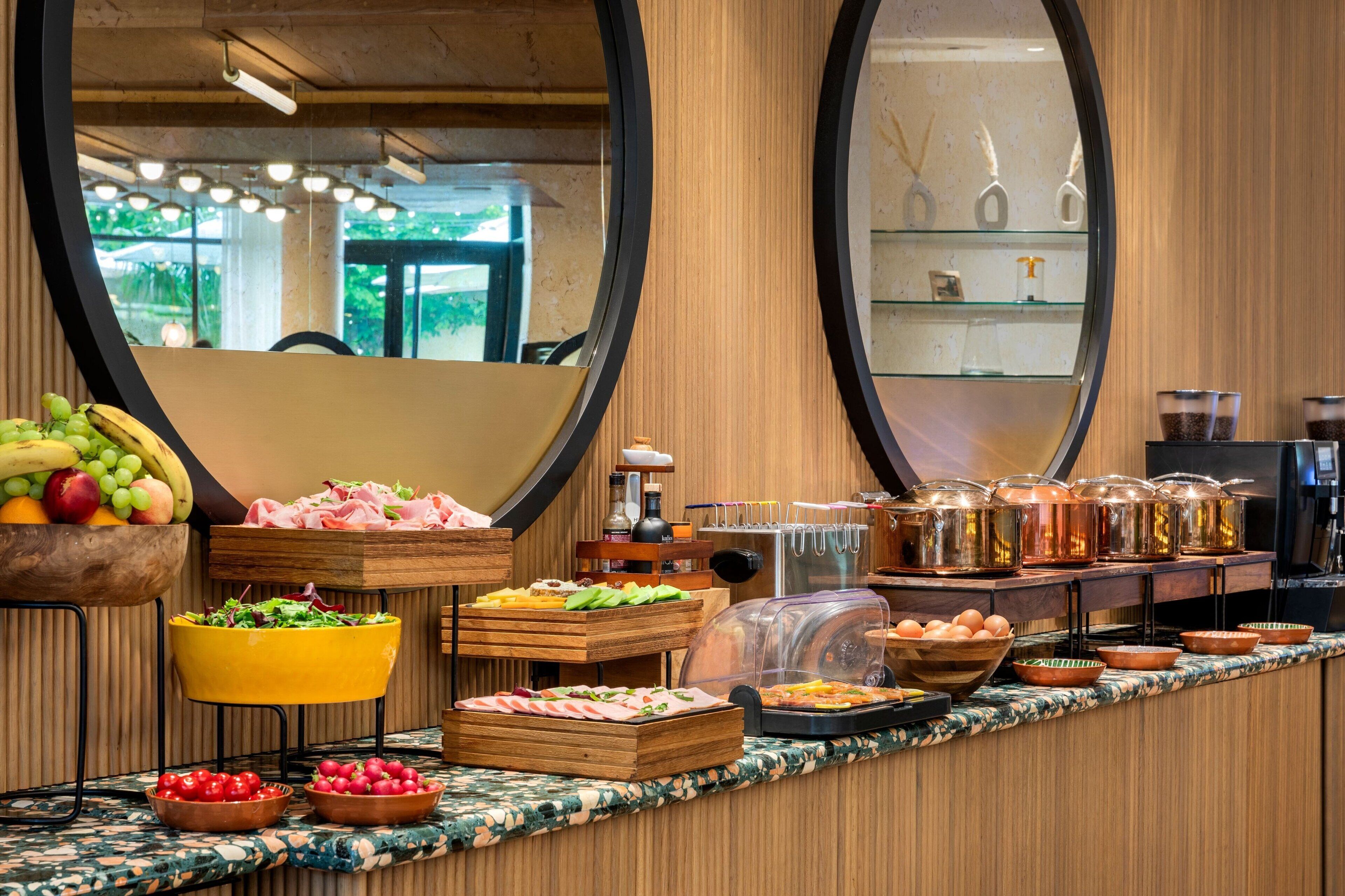 Buffet com diversos alimentos e um espelho refletindo o ambiente.