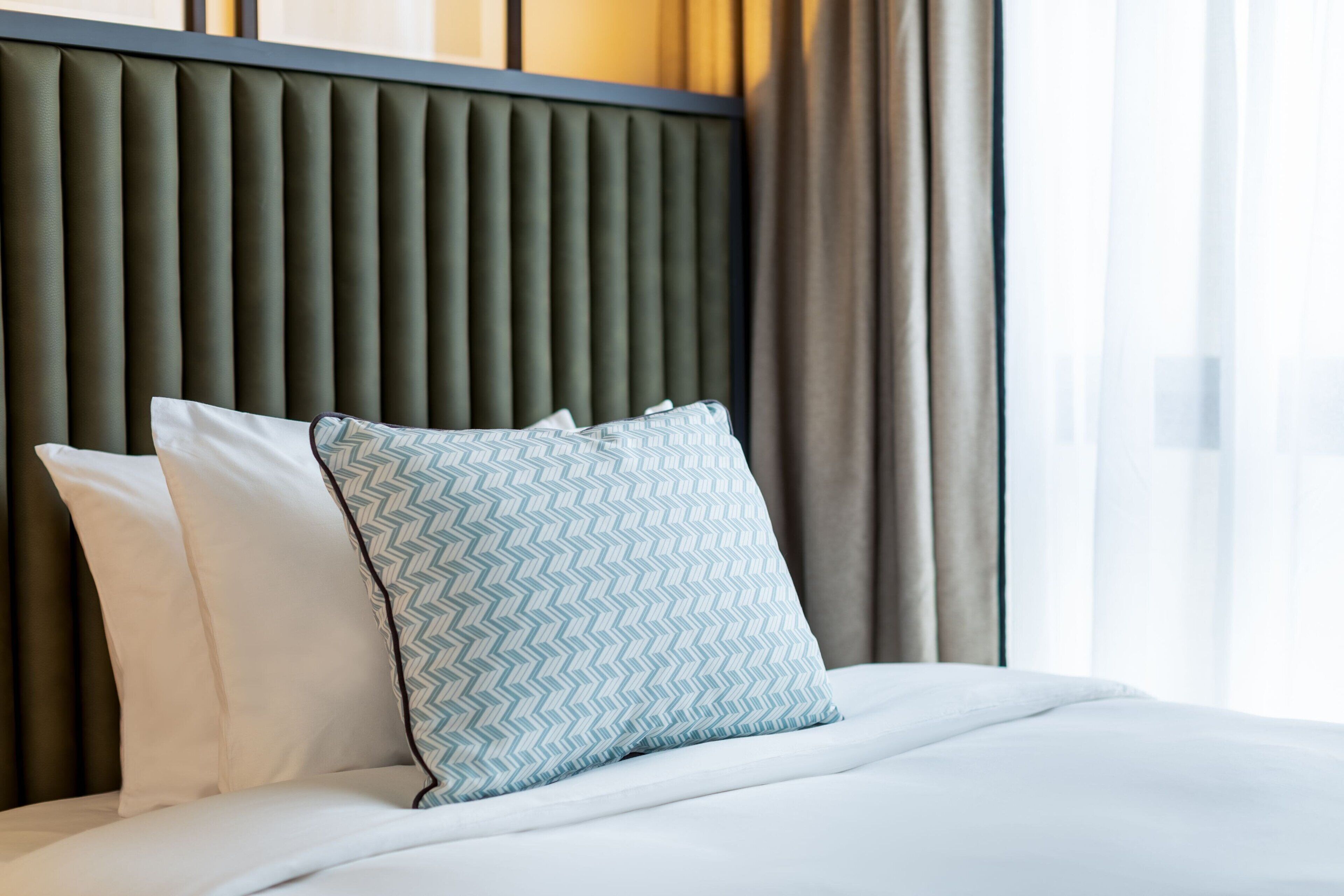 Un lit bien fait, avec un oreiller et un coussin à motifs chevrons.
