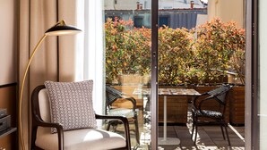 Un balcon moderne avec une porte vitrée, une table, deux chaises et un lampadaire.