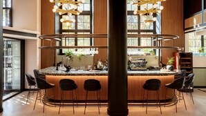 Un espace bar moderne doté d’un îlot central, de tabourets de bar et de luminaires suspendus.