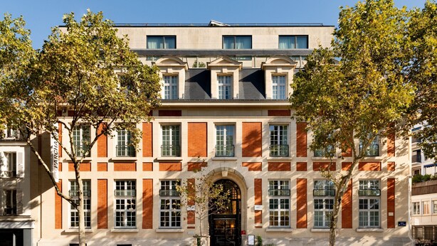 Un bâtiment historique à la façade symétrique, doté de grandes fenêtres et d’une entrée centrale.