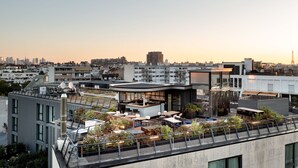 Une terrasse sur le toit avec des sièges en plein air, un bar entièrement vitré et une vue sur le panorama urbain.