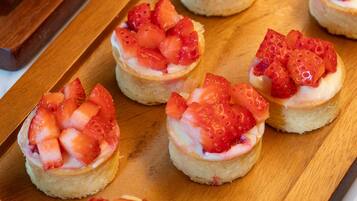 Una tabla de madera con varios pequeños pasteles cubiertos de fresas.