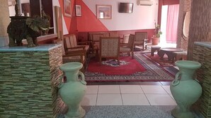 Un salon avec un mur d’accent rouge, un grand tapis et deux vases.