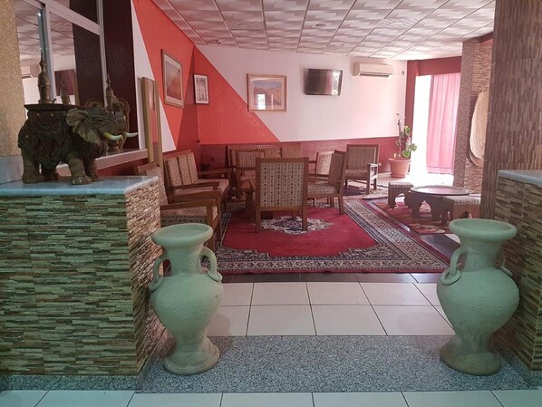 Ein Wohnzimmer mit roter Akzentwand, einem großen Teppich und zwei Vasen.