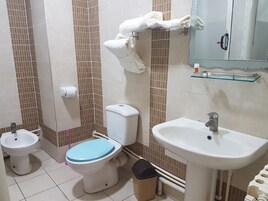 Un baño con inodoro, bidé, lavamanos y un perchero para toallas.