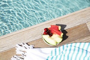 A wooden deck with a white towel and a plate of fruit by a pool. - Ofelias Hotel (Barcelona)