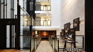 A modern hotel lobby with a wooden floor, glass railings, a staircase, and artwork on the walls. - Ofelias Hotel (Barcelona)