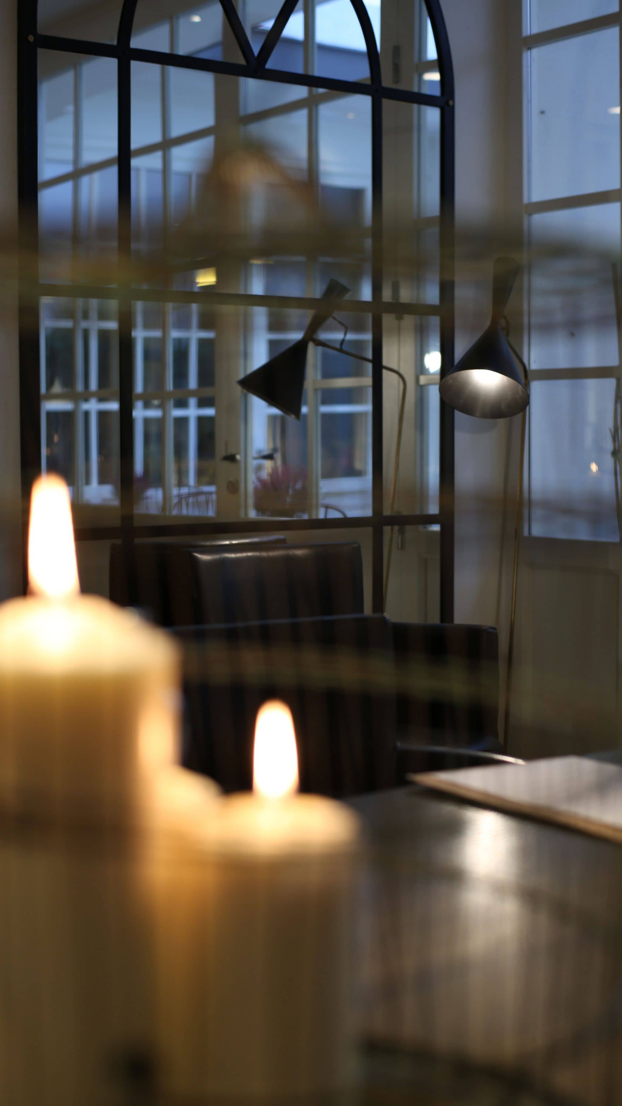 A room with a large window, a table, and two lamps.