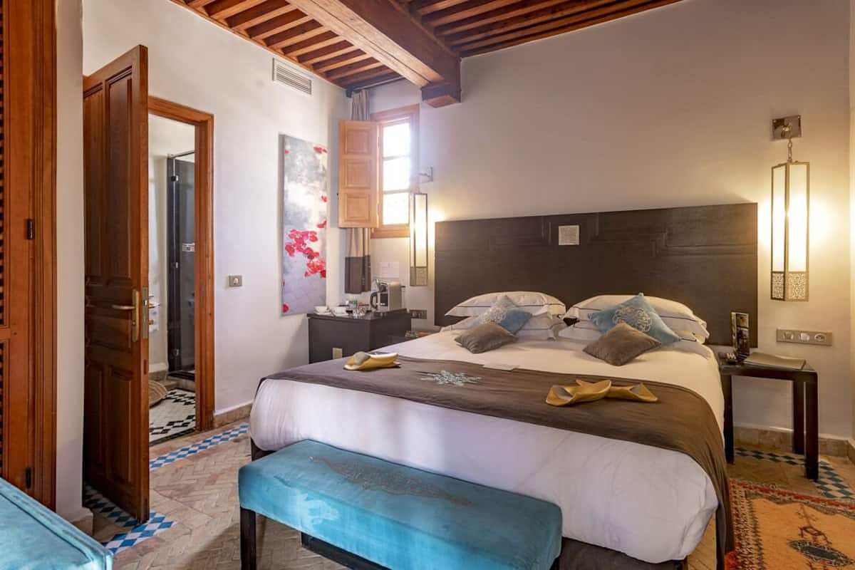 Une chambre à coucher avec un grand lit, une tête de lit en bois, des tables de chevet et un banc.
