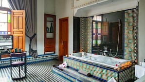 Un baño con una bañera grande, un espejo y piso de baldosas.