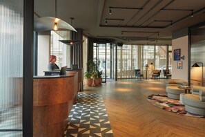 A modern hotel lobby with a reception desk, seating area, and large windows. - Hotel Indigo Newcastle by IHG (Newcastle-upon-Tyne)