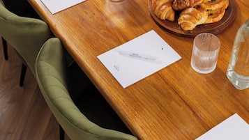 A wooden table with croissants, a glass, and a brochure.