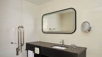 A modern bathroom with a large mirror, a sink, and a toilet.