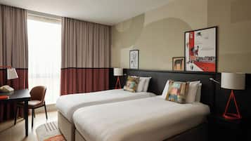 Une chambre d’hôtel avec deux lits, un bureau et une chaise.
