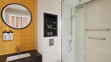 A bathroom with a glass shower enclosure, a sink with a black vanity, and a mirror with a black frame.