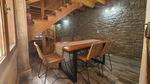 A wooden staircase leading to a dining area with a stone wall backdrop. - Hosteria Hueney Ruca (San Martín de los Andes)
