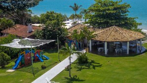 Una propiedad frente a la playa con un área de juegos, un espacio de estar cubierto y vista al océano.