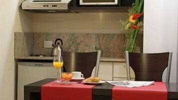 Una cocina moderna con una mesa de comedor, dos sillas, un microondas, una cafetera y un jarrón con flores.