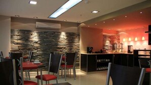 Un restaurant moderne avec des murs en pierre, des chaises rouges et un coin bar.