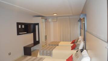 Una habitación de hotel moderna con dos camas, un televisor de pantalla plana, un equipo de aire acondicionado y un espejo grande.