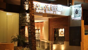 L’extérieur de Sol de Piedra se distingue par sa façade en pierre, son entrée en verre et une enseigne indiquant qu’il propose des appartements, des suites et des services de spa.